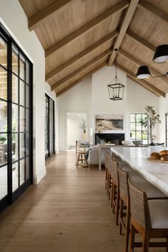 an open kitchen and dining room area with wood beams on the ceiling, white counter tops, and wooden flooring