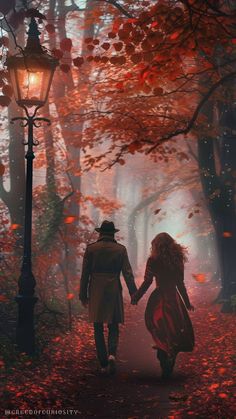 a man and woman holding hands walking in the woods with red leaves on the ground