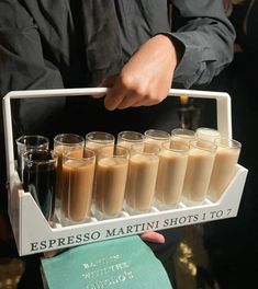 a person holding a tray with shots in it