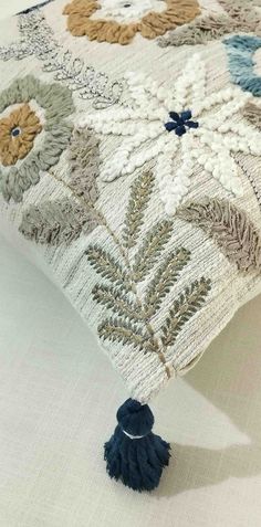 an embroidered pillow with tassels on it