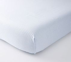 an unmade bed with white sheets and blue stripes on the bottom half of it