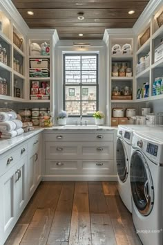 a washer and dryer in a kitchen with white cabinets, wood flooring and open shelving