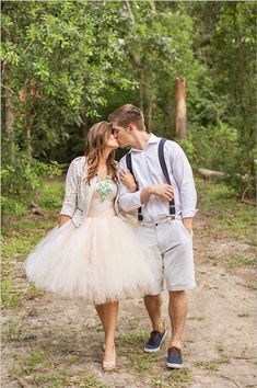 a man and woman are walking through the woods in tutu skirts, suspenders and shoes