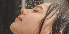 a woman is taking a shower with her head in the air while she's wet