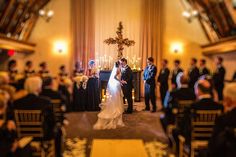 a bride and groom standing in front of the alter at their wedding ceremony, surrounded by guests