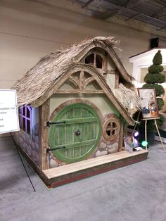 a small house made out of wood and grass with a sign in front of it