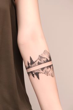 Explore 30 stunning small mountain tattoo designs perfect for both women and men, offering a mix of simple and intricate ideas. Whether you're looking for a tiny mountain tattoo with a sun, a simple pine tree design, or something with an ocean or wave, these tattoos are ideal for placement on the shoulder, ankle, finger, or forearm. You’ll also find creative options featuring nature elements like cacti, flowers, and waterfalls, making each design uniquely meaningful. Simple Manly Tattoos, Mountain Band Tattoo Design, Men Simple Tattoo Ideas, Mountain Wrap Tattoo, Leg Mountain Tattoo, Mother Daughter Mountain Tattoos, Tattoo Mountain Ocean, Trees Tattoo Forearm, Book Mountain Tattoo