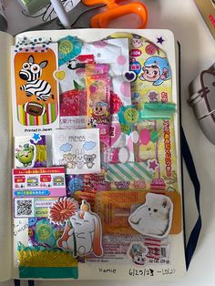 an open notebook covered in lots of stickers and magnets on top of a table