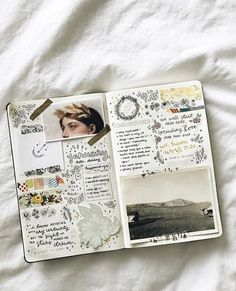 an open notebook with pictures and writing on it, sitting on a bed sheet covered in white sheets