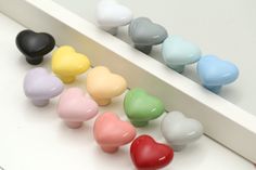 there are many small hearts on the shelf next to each other, all in different colors