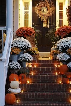 the front steps are decorated with pumpkins and flowers for halloween decorations, while candles light up the walkway