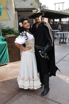 a man and woman dressed up as pirates pose for a photo on the sidewalk in front of a restaurant