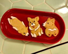 three cookies in the shape of dogs on a red tray