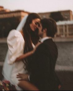 a man and woman standing next to each other in front of a body of water