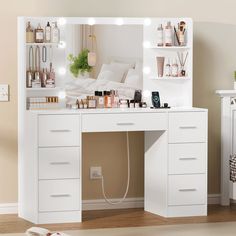 a white vanity with lights on it in front of a mirror and shelves filled with cosmetics