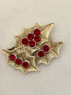 Dodds Holly Leaves Red Berries Vintage Holiday Costume Brooch.  In excellent and unworn condition, a substantial 1950s Christmas pin measuring 2 1/4" wide by 1 3/4" tall.  The gold tone plate and sparkling Holly red rhinestones are bright and sparkling. The pin back is straight and strong, the clasp locks securely. Will come wrapped in a cellophane gift bag. Red Vintage Holiday Jewelry, Vintage Red Jewelry For Holidays, Red Vintage Jewelry For Holidays, Vintage Red Pins For Gifts, Vintage Red Pins As Gift, Vintage Red Pins For Gift, Vintage Red Pins For Party, Vintage Red Brooches For Festive Occasion, Vintage Red Jewelry For Christmas