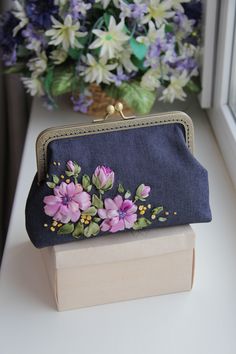 a purse sitting on top of a wooden box next to a flower pot filled with purple flowers