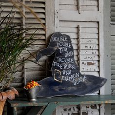 a potted plant sitting on top of a table next to a chalkboard sign