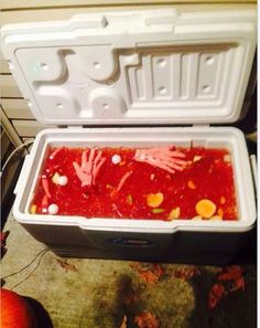 a cooler filled with lots of red food next to an orange and white container on the ground