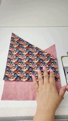 a woman is using a sewing machine to sew a piece of fabric with pink nail polish