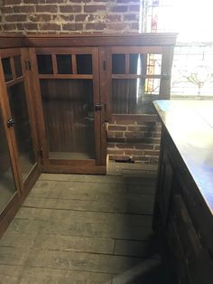 an empty kitchen with brick walls and wooden cabinets in the center, next to a counter top