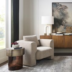 a living room with a large painting on the wall next to a chair and side table