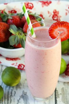 a strawberry and lime smoothie in a glass with a straw next to it on a plate