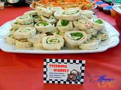 there is a plate full of food on the table at this birthday party that includes rolls and veggies