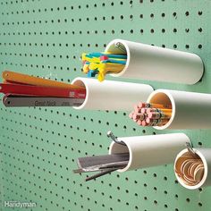 three pencils, scissors and pens are hanging on a pegboard with holes in it