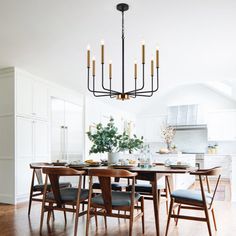 a dining room table with chairs and a chandelier hanging from the ceiling above it