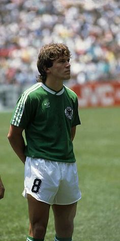 a man standing on top of a soccer field wearing a green shirt and white shorts