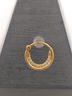 a pair of gold hoop earrings on top of a piece of wood with clear stones