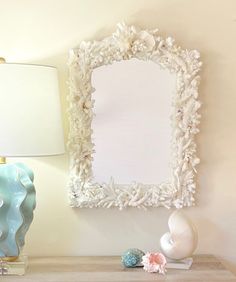 a table with a lamp, mirror and seashells on it