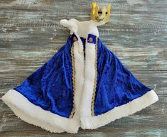 a blue and white dress with a crown on it's head sitting on a wooden surface