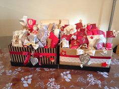 two boxes filled with gifts sitting on top of a table next to a dog paw