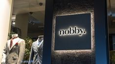 two suits are displayed in front of a sign that says nobby