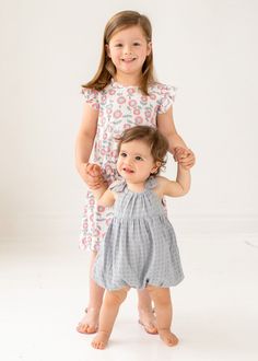 This charming sleeveless romper by Mabel and Honey is a delightful ensemble for your little one. Fashioned from breezy grey cotton gauze with a delicate check pattern, it features playful ruffle accents on the straps for a sweet touch. The romper's light hue and soft texture make it perfect for sunny days. Fabric Care50% VISCOSE 50% COTTON | Machine Wash Cold | Line Dry | Do Not Bleach Spring Gingham Bubble Romper With Ruffles, Spring Cotton Bubble Romper With Ruffled Straps, Playful Gingham Bubble Romper For Spring, Spring Playful Bubble Romper With Flutter Sleeve, Summer Bubble Romper With Smocked Back For Playwear, Playful Bubble Romper With Smocked Back, Playful Summer Bubble Romper With Smocked Back, Sleeveless Ruffle Bubble Romper For Playdate, Spring Gingham Bubble Romper For Playtime