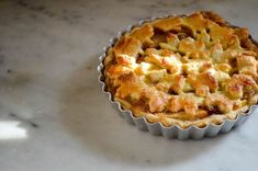 a pie sitting on top of a white counter next to a cupcake tin filled with food