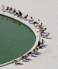 people are sitting on lawn chairs by the water