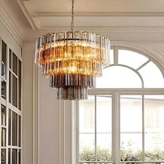 a chandelier hanging from the ceiling in a living room with windows and doors