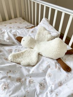 a stuffed animal laying on top of a bed next to pillows and pillowcases