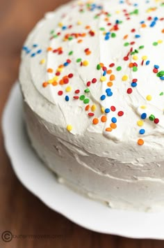 a cake with white frosting and colorful sprinkles sitting on a plate