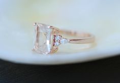 a pink diamond ring sitting on top of a white plate