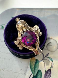 This charming Art Nouveau bird ring centers on a glowing 1.55 carat pinkish-purple rhodolite garnet held by a pair of sinuous leaves that double as stylized wings. Circa 1900, crafted in burnished 14k gold, hand textured throughout. Currently a ring size 3. Garnet: 7.45 x 7.45 x 3.96 mm, minor surface wear as shown Weight: 4.1 grams Measurements: 21 mm north to south Notes: previously sized, no markings Art Nouveau Bird, Bird Ring, Bird Rings, Nouveau Jewelry, Art Nouveau Jewelry, Gold Hand, Rhodolite Garnet, Rings Statement, Garnet