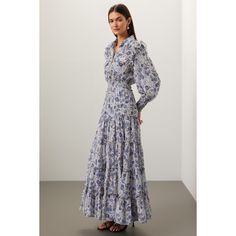 Blue floral chiffon (100% Polyester). A-line. Long sleeves. Collar. Front button closure. 54.5" from shoulder to hemline. Made in the USA of imported fabric. Blue Elegant Maxi Dress With Smocked Bodice, Elegant Blue Maxi Dress With Smocked Bodice, Elegant Billowy Floral Print Dress, Elegant Billowy Floral Print Maxi Dress, Elegant Flowy Floral Maxi Dress, Floral Print Flowy Maxi Dress For Daywear, Blue Flowy Feminine Dress, Feminine Blue Dress With Flowy Skirt, Feminine Blue Flowy Dress