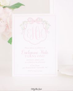 a pink floral monogrammed wedding card on a table