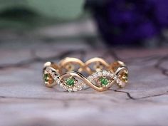 a gold ring with green and white stones on it's sides, sitting on top of a table