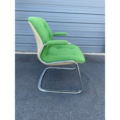 a green chair sitting in front of a garage door