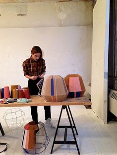 a woman is sitting at a table with many different colored objects on top of it