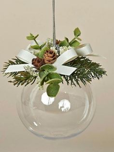 a clear glass vase with pine cones and greenery in it, hanging from the ceiling